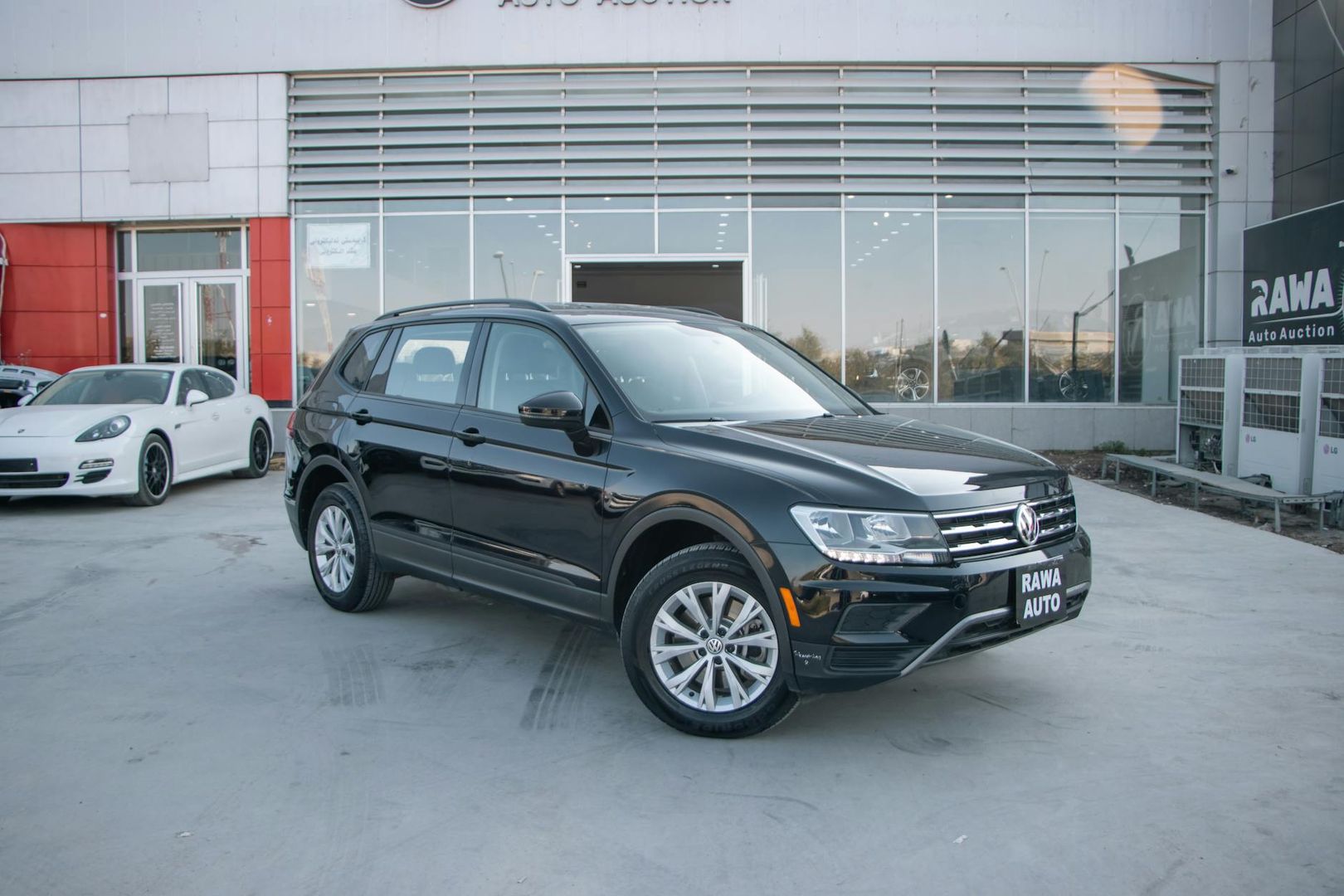 Svart Volkswagen Tiguan parkerad utanför en anläggning för fordon auktioner.