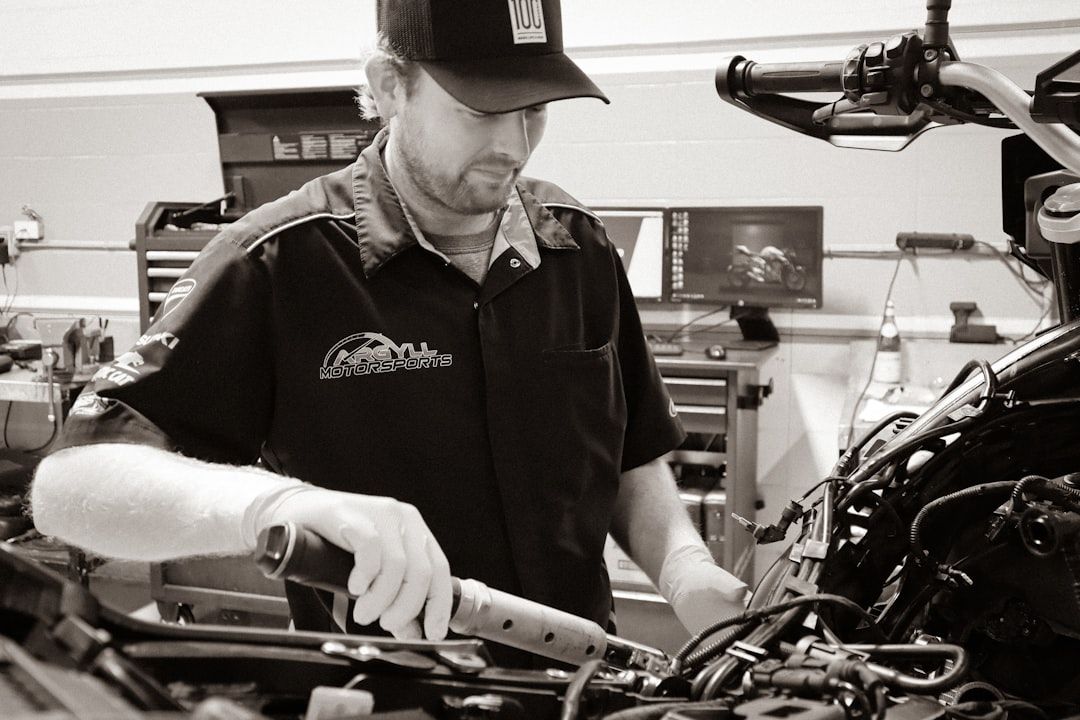 En mekaniker inspekterar motorn på ett fordon i en verkstad.